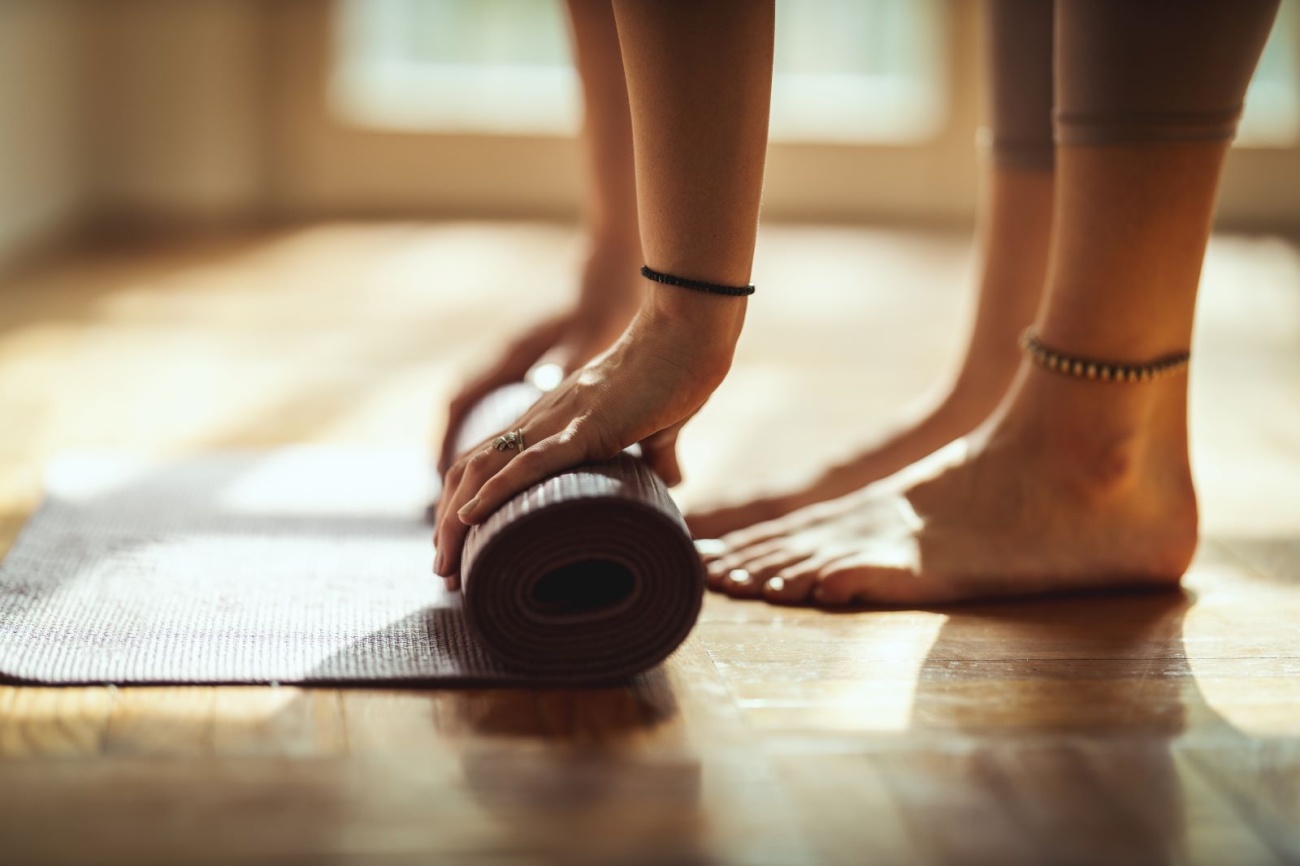 close-up photo of a woman rolling up a yoga mat